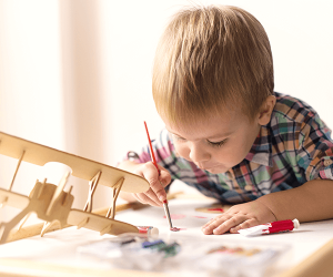 toddler painting with a model plane