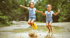 two preschool kids jumping in puddles